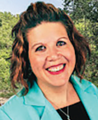 Woman smiling outdoors in turquoise blazer.