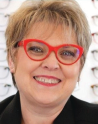 Smiling woman with red glasses in optician's office.