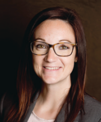 Smiling woman wearing glasses and a blazer.