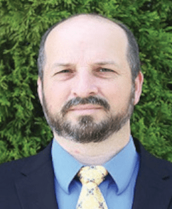 scaled_spurlockv2 Man in suit with green plant background